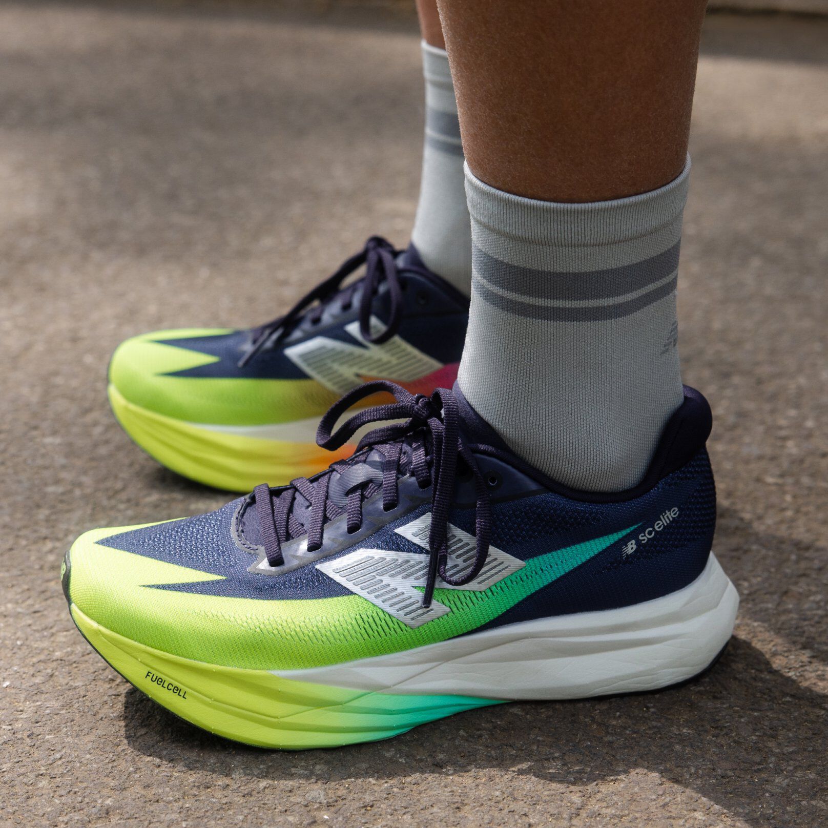 Two people posing indoors against a textured backdrop, wearing casual athletic outfits and sneakers. 